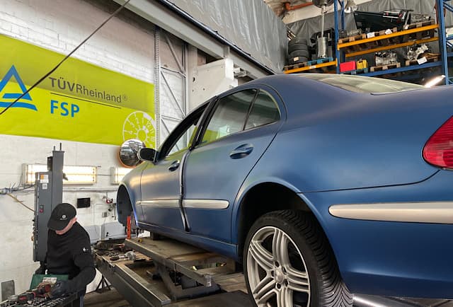 Mechaniker hebt Mercedes E-Klasse auf Hebebuehne – Bremsanlage wird geprueft