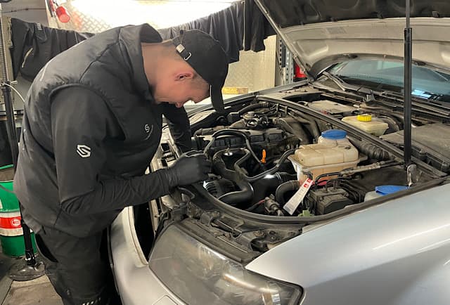 Mechaniker bei Demontage Zahnriemen Audi A4 – Motorraum geoeffnet, systematische Arbeit